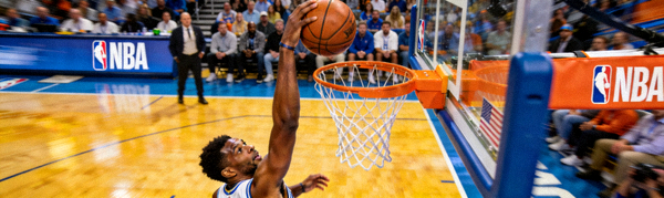NBA篮球比赛现场，球员高高跃起完成扣篮